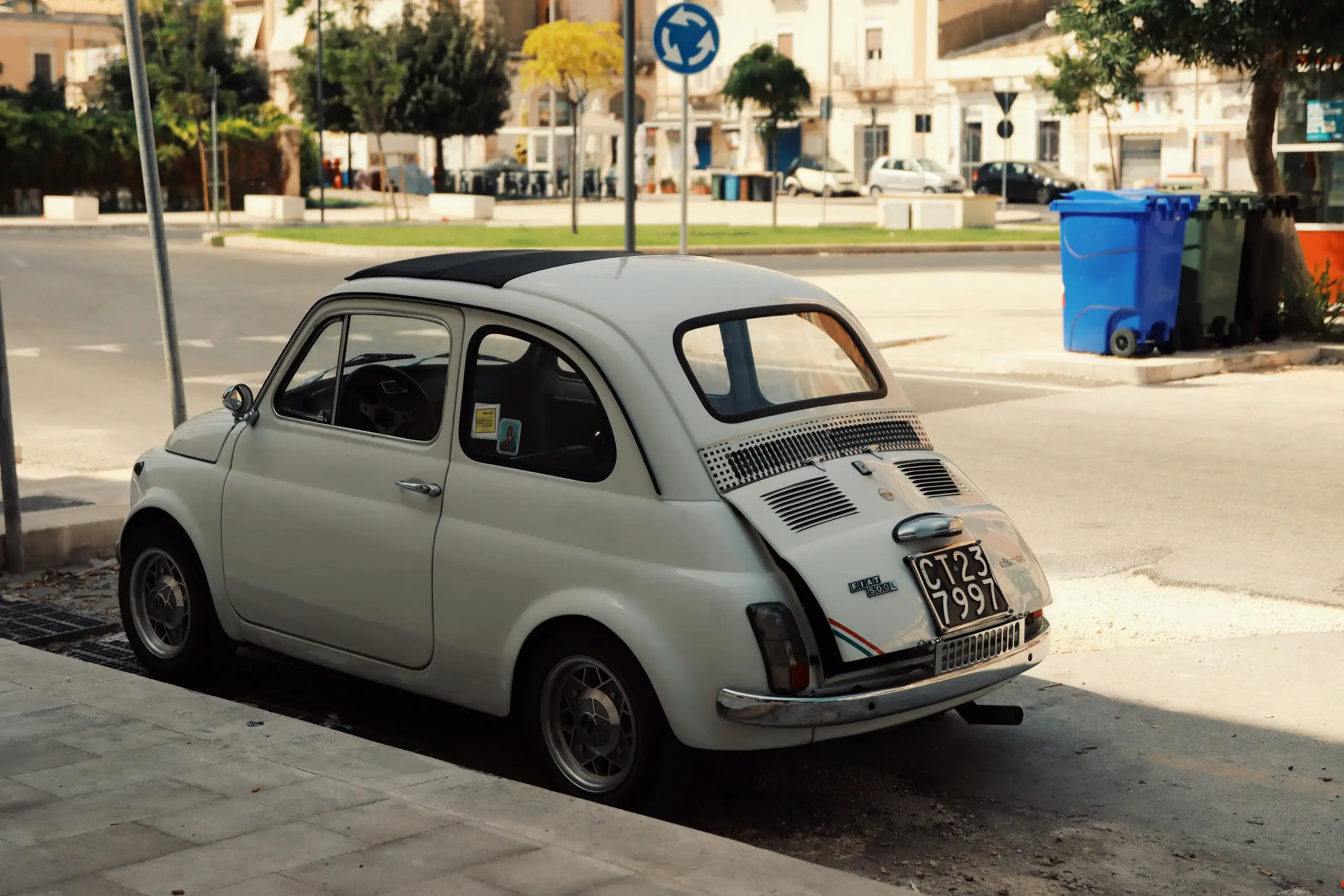 Biały zabytkowy Fiat 500 zaparkowany na włoskim placu